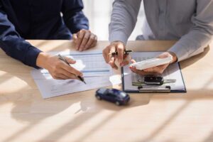 Adults review life insurance paperwork beside a calculator and family budget documents at a kitchen table.