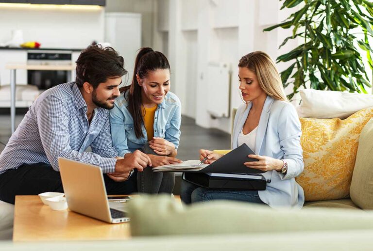 A couple reviews life insurance papers and household financial documents at a kitchen table.